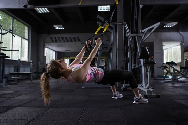 Spor Salonundaki Trx Antrenörü Üzerinde Düşük Sıra Egzersizi Yapan Bayan — Stok fotoğraf