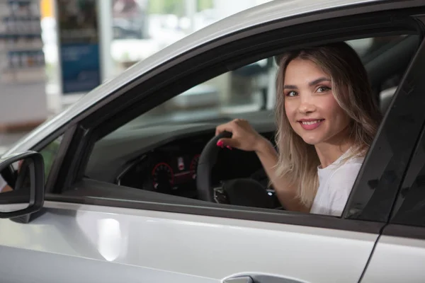 Kameraya Gülümseyen Genç Bir Kadın Galeride Yeni Bir Otomobilin Içinde — Stok fotoğraf