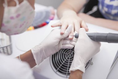 Manikürcünün tırnak etlerini çivi matkabıyla keserken çekilmiş bir fotoğrafı.