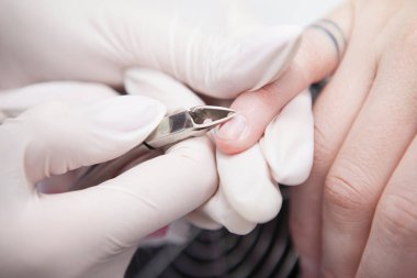 Kadın müşterinin manikürcüsü tarafından tırnak etlerinin alındığı yakın plan.