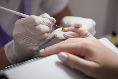 Profesyonel bir manikürcünün müşterisi için neon çivi çakması.