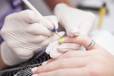 Manikürcünün neon oje sürdüğü yakın plan.