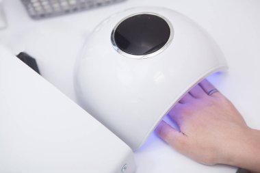 UV manikür lambasının altındaki bir elin kesilen üst görüntüsü