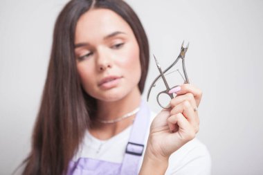 Kadın manikürcü, elinde tırnak uçlarıyla makas tutuyor.