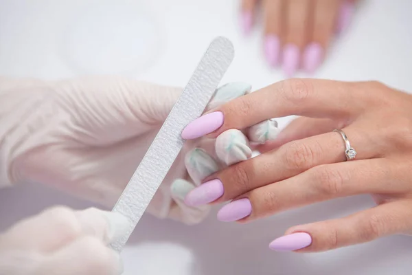 Close up of manicurist filing nails of female client