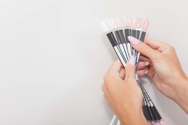 Tarafsız tırnak cilası renginde palet tutan kadın elleri kesilmiş.