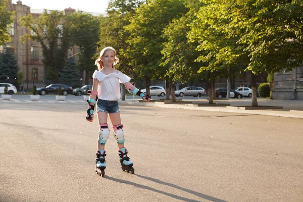 Petite Belle Fille Sur Patins à Roulettes Dans Un Casque Et Protection Des  Mains Et Des Pieds Dans Un Skate Park