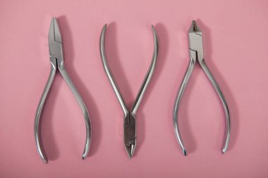 Üst görünümde pembe arka planda diş pensesi kapat