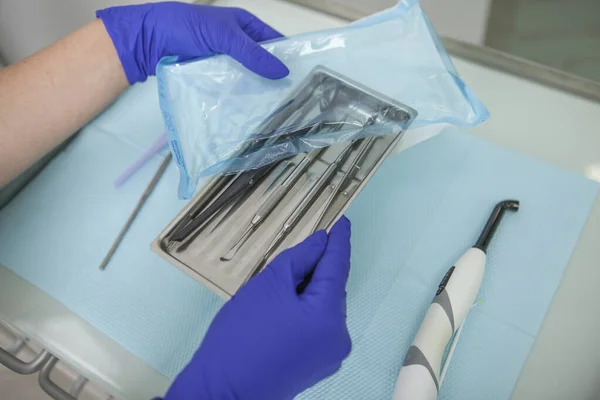 Close up of dentists hands unpacking sterile instruments for teeth examination