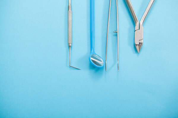 Top view cropped close up of dentists tools on blue background, copyspace