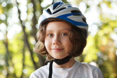 Gülümseyen, koruyucu kask takan sevimli bir çocuğun yakın çekimi.