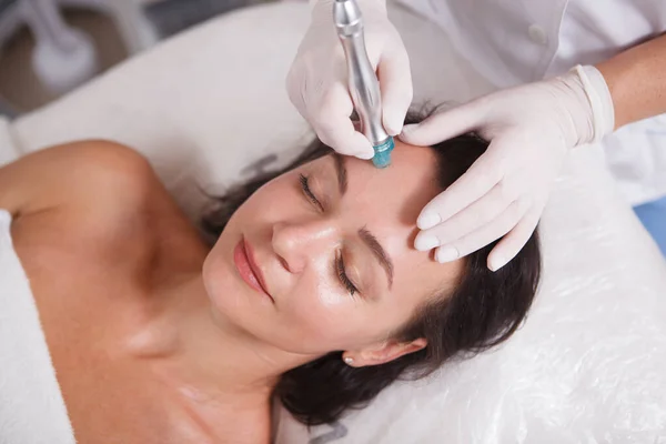 Top view close up of a mature woman smiling, getting hydra pores facial cleanse