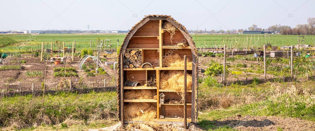 An insect hotel in front of a botanical garden and a faraway horizon