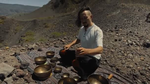 一个年轻的亚洲人在大自然的观光山上弹奏着Tibedt铜杯 — 图库视频影像