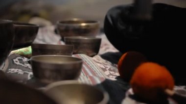 Tibedt çalan genç bir Asyalı doğadaki bir dağda bakır bardaklar söylüyor.