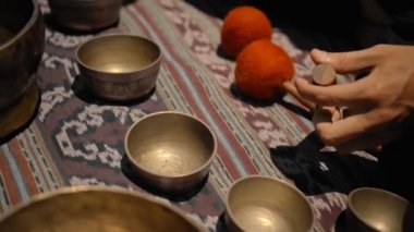 Tibedt çalan genç bir Asyalı doğadaki bir dağda bakır bardaklar söylüyor.