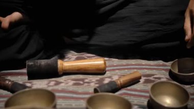 Tibedt çalan genç bir Asyalı doğadaki bir dağda bakır bardaklar söylüyor.