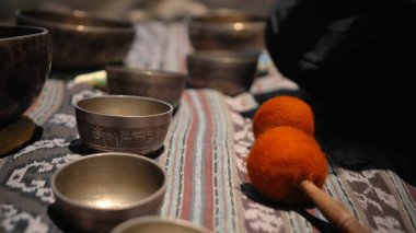 Tibedt çalan genç bir Asyalı doğadaki bir dağda bakır bardaklar söylüyor.