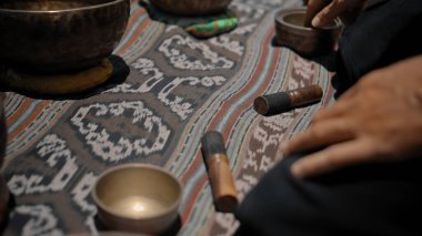 Tibedt çalan genç bir Asyalı doğadaki bir dağda bakır bardaklar söylüyor.