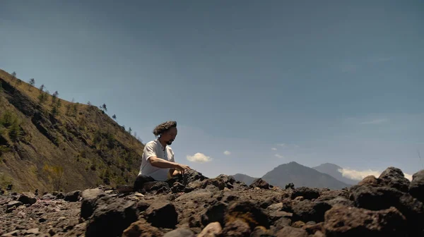 A young Asian guy playing Tibedt singing copper cups on a viewing mountain in nature