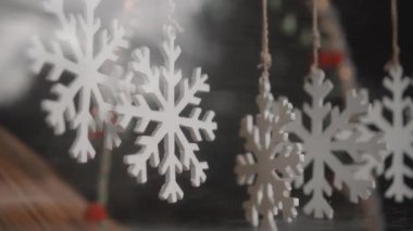Evin camının arkasındaki ipliğe asılı küçük beyaz bir Noel mücevheri.