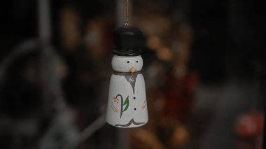 Küçük beyaz Noel oyuncakları. Kardan adamlar evdeki camın arkasında bir ipliğe tutunuyorlar.