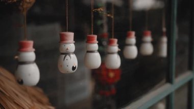 Küçük beyaz Noel oyuncakları. Kardan adamlar evdeki camın arkasında bir ipliğe tutunuyorlar.