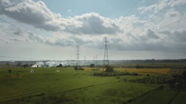 Yeşil pirinç tarlasında yeni inşa edilmiş bir elektrik iletim kulesinin hava aracı görüntüsü