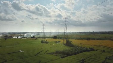 Yeşil pirinç tarlasında yeni inşa edilmiş bir elektrik iletim kulesinin hava aracı görüntüsü