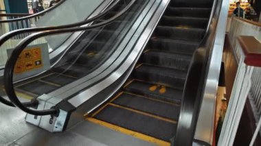 Alışveriş merkezindeki siyah merdiven basamakları, sosyal mesafeyi korumak için bir tabela.