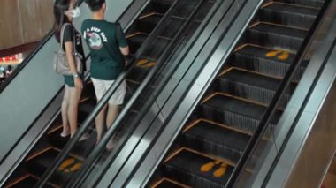 Kuta, Kabupaten Badung, Bali, Endonezya - 6 Kasım 2020: Toplumsal mesafeyi korumak için ayak izi işareti olan bir alışveriş merkezinde siyah merdiven yürüyen merdiven