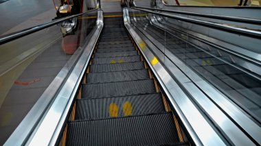 Alışveriş merkezindeki siyah merdiven basamakları, sosyal mesafeyi korumak için bir tabela.