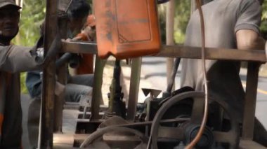 Pesadan, Rendang, Bali, Endonezya - 10 Kasım 2020: 4K Endonezyalı erkek tatilcilerin el yapımı ekipman ve borularla petrol ürettikten sonraki videoları