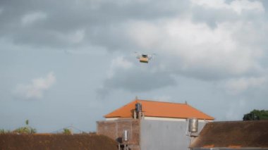 4K video görüntüleri, elinde karton bir paketle gökyüzü teslimatında uçan bir İHA 'nın