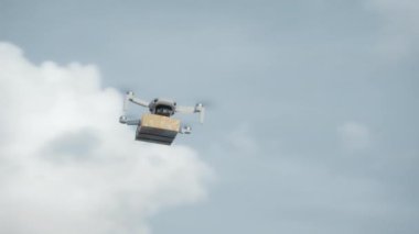 4K video görüntüleri, elinde karton bir paketle gökyüzü teslimatında uçan bir İHA 'nın