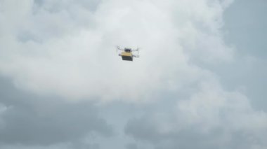 4K video görüntüleri, elinde karton bir paketle gökyüzü teslimatında uçan bir İHA 'nın