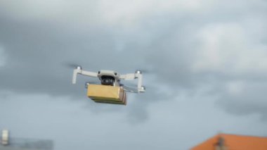 4K video görüntüleri, elinde karton bir paketle gökyüzü teslimatında uçan bir İHA 'nın