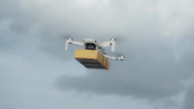 4K video görüntüleri, elinde karton bir paketle gökyüzü teslimatında uçan bir İHA 'nın