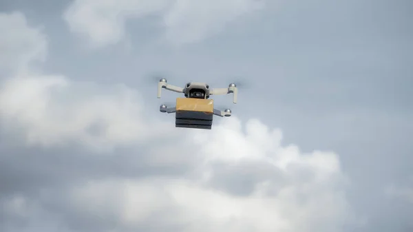 Elinde karton bir paketle gökyüzünde uçan bir hava aracının fotoğrafı.