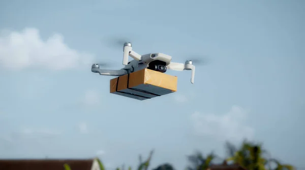 Elinde karton bir paketle gökyüzünde uçan bir hava aracının fotoğrafı.