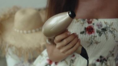 Genç Avrupalı bir kız arka bahçede elektrikli el bakım aletini alır kanepede oturur ve bir ovalama başlığı giyer.