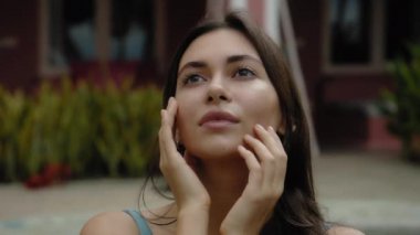 Yüzme havuzuna yakın oturan, yüzme havuzunda oturan, yumuşak elleri ve parmakları olan genç ve güzel Avrupalı esmer bir kızın yüzü.