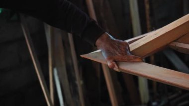 4K görüntülerinde, Yaşlı Usta 'nın buruşuk elleri, atölyede çekiçle tahta tahtaya çivi çakıyor.