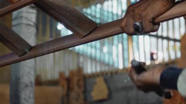 4K görüntülerinde, Yaşlı Usta 'nın buruşuk elleri, atölyede çekiçle tahta tahtaya çivi çakıyor.