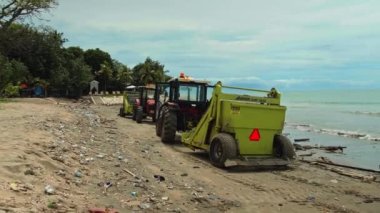 Kuta, Badung, Bali, Kuta Beach Endonezya - 4 Ocak 2021: Kuta kentindeki Bali adasında denizden plastik çöp attıktan sonra kumdaki deniz plajlarını temizleyen traktör teknisyeni