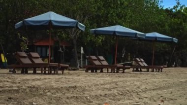 Sabahın erken saatlerinde sahilde katlanmış plaj şemsiyeleri ve boş güneşlikler.