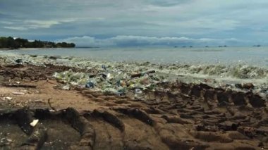 Plaj kirliliği. Plastik çöp ve deniz sahilindeki diğer çöplerin 4K videosu. Ekolojik kavram