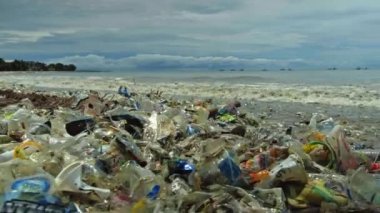 Plaj kirliliği. Plastik çöp ve deniz sahilindeki diğer çöplerin 4K videosu. Ekolojik kavram