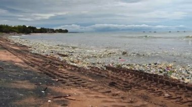 Plaj kirliliği. Plastik çöp ve deniz sahilindeki diğer çöplerin 4K videosu. Ekolojik kavram