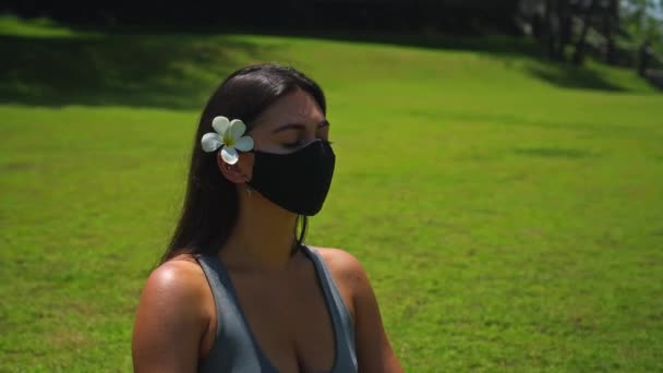 유럽의 소녀는 얼굴에 보호용 마스크를 연꽃을 풀밭에 속에서 요가를 — 비디오